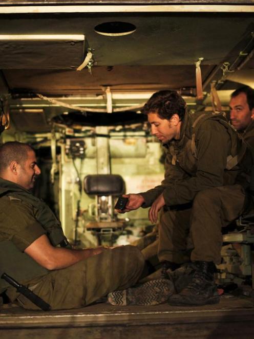 Israeli soldiers sit in an Armoured Personnel Carrier (APC) at a staging area outside the...