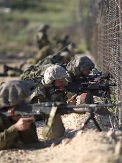 Israeli troops take position along the border fence between Israel and Syria as Syrian...