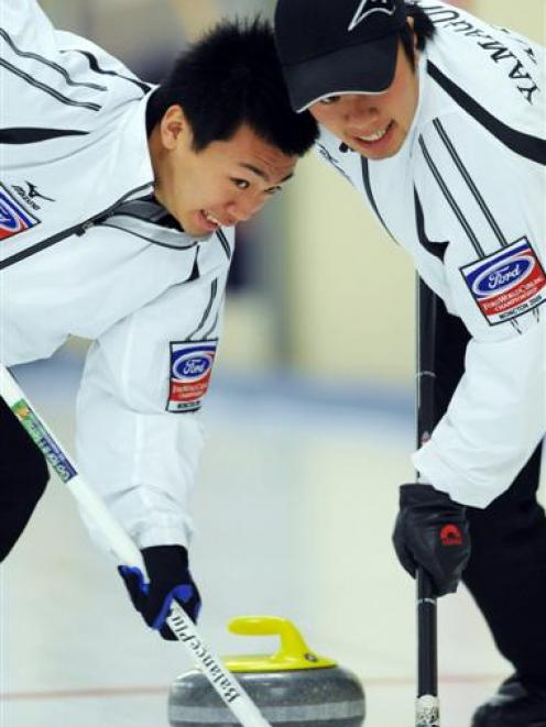 Japanese curlers Tetsuro Shimizu (left) and Tsuyoshi Yamaguchi work hard on the ice at the...