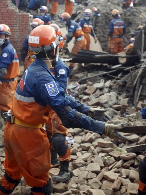Japanese rescue team members work to clear debris while searching in Lalitpur for victims of the...