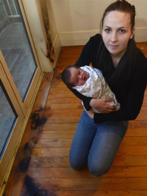 Jenna Pope, with her baby son, beside  the fire damage in the bedroom of her Brighton home. Photo...