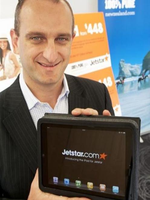 Jetstar Group chief executive Bruce Buchanan holds one of the Apple iPads the airline will offer...