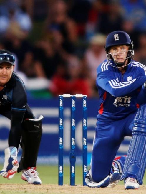 Joe Root of England lines up a reverse sweep shot watched by Brendon McCullum of New Zealand...