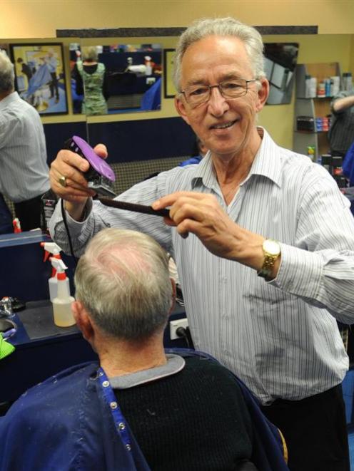 John Spek, of Dunedin, cuts client John Garraway's hair on his last day yesterday. Photo by Peter...