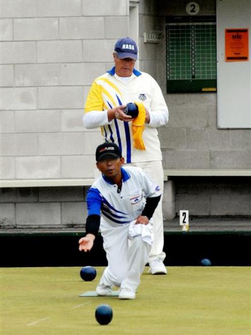 Joko Susilo (Andersons Bay) delivers a bowl while Lou Robinson (Leith) looks on during the Bowls...
