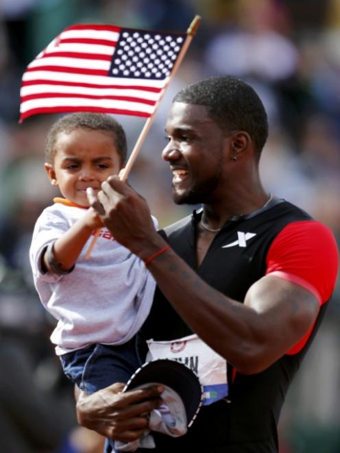 Justin Gatlin hands his son Jace a US flag as he celebrates winning the men's 100m during the US...