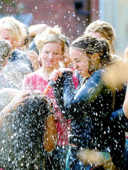 Katie Rademaker hoses mud off fellow Selwyn students after the college's annual Leith run on...