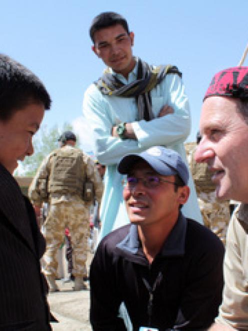 New Zealand Prime Minister John Key talks to a boy in the streets of Bamiyan
