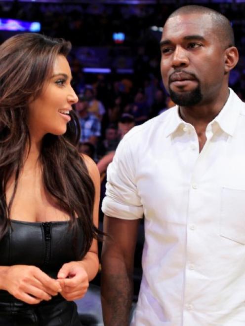 Kim Kardashian (L) and attend a Los Angeles Lakers basketball game in May. The pair are expecting...