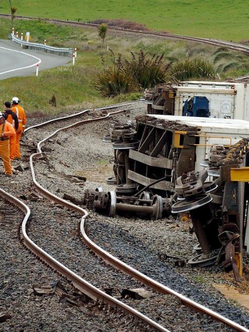 Kiwirail workers wait for heavy lifting equipment at the scene of a derailment on the main truck...