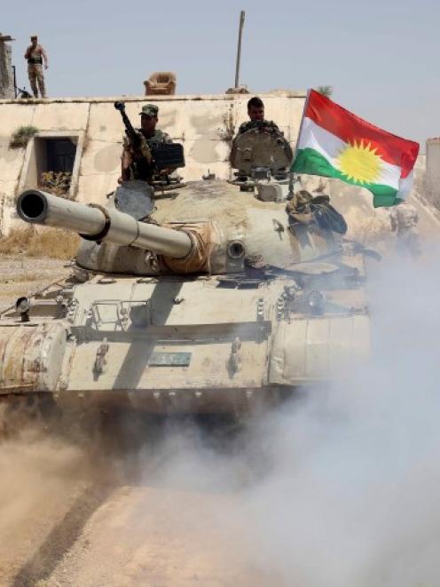 Kurdish Peshmerga troops travel in a tank as they secure an area in the town of Sulaiman Pek in...