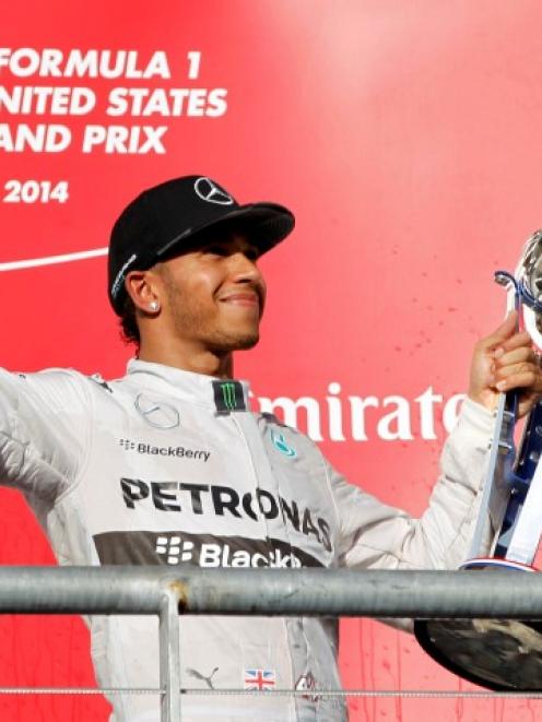 Lewis Hamilton holds up his trophy and a bottle of champagne after winning the US Grand Prix in...