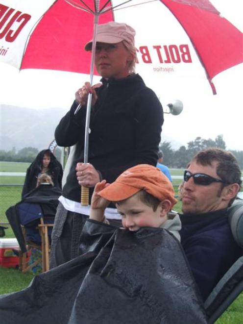 Liam (4) and Craig Direen, of North Otago, and Lisa Direen (Christchurch) keep dry during several...