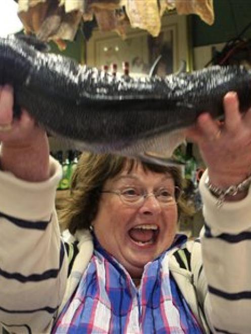 Linda Hunter, of Zionsville, Indiana, lifts a salmon after catching it at the Pike Place Fish...