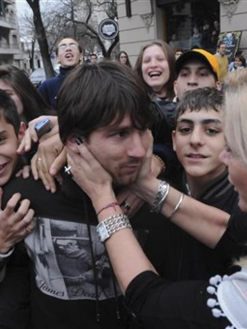 Lionel Messi, centre, is grasped by an unidentified woman as he leaves a restaurant in Rosario,...