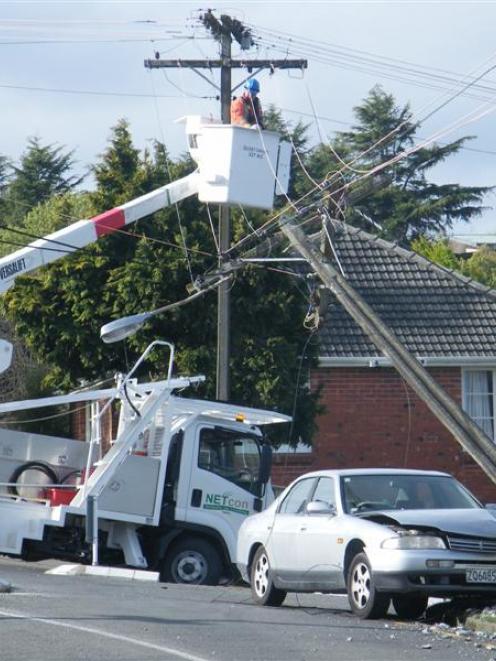 Live, dangling power lines posed an extreme danger to the driver of this car after it toppled a...