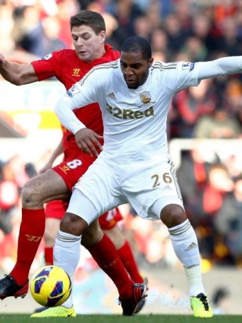 Liverpool's Steven Gerrard (L) challenges Swansea City's Kemy Agustien during their English...