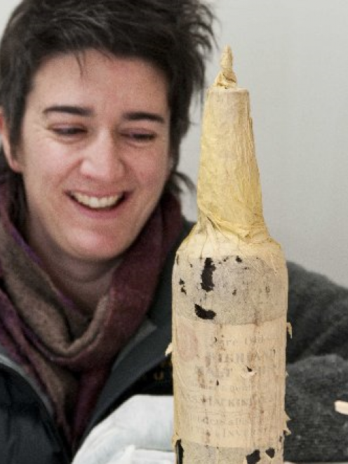 Lizzie Meek, Antarctic Heritage Trust artefacts manager admires a bottle of Mackinlay's Highland...