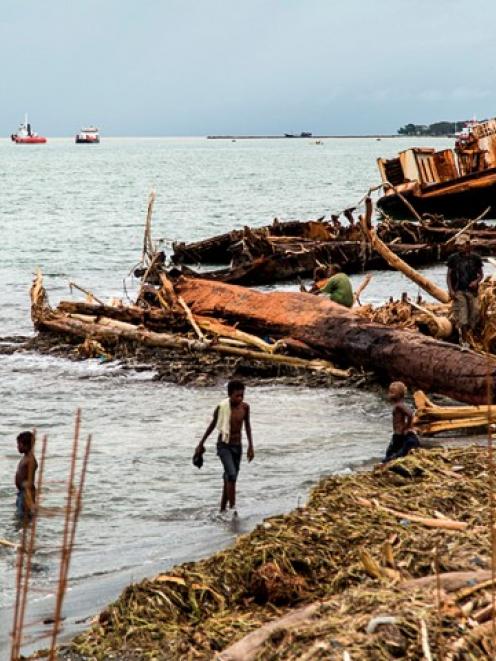 Locals walk among debris washed ashore after severe flooding near the capital Honiara in the...