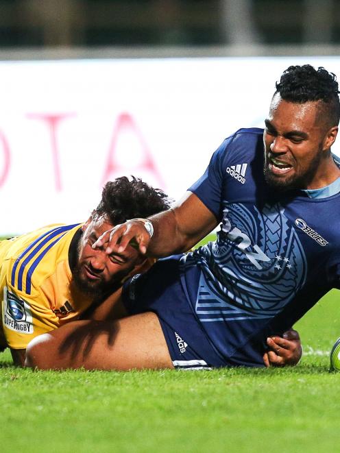 Lolagi Visinia of the Blues scores a try in the tackle of Matt Proctor of the Hurricanes during...