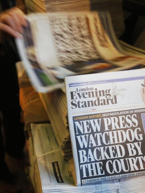 Lord Justice Brian Leveson appears on the front page of a stack of evening newspapers after his...