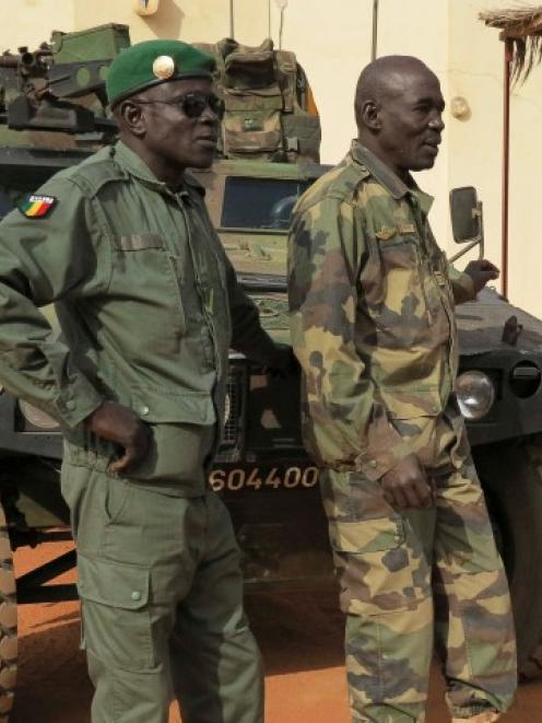 Malian military soldiers stand near an armoured vehicle belonging to the French Army at the...