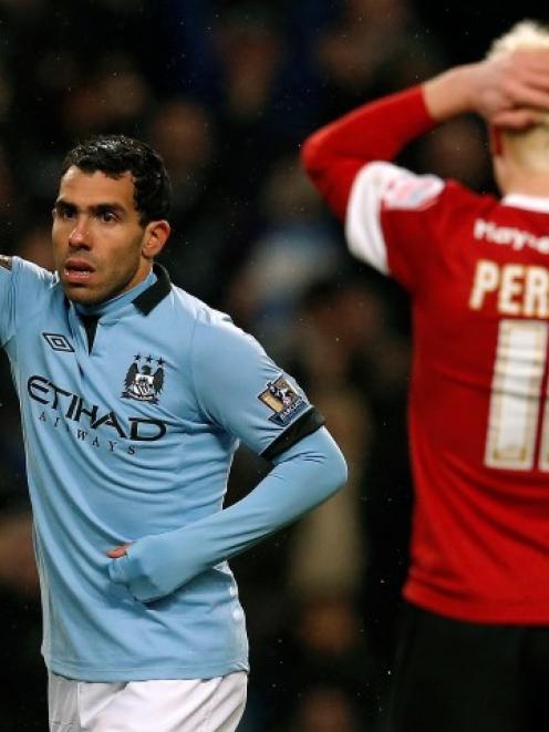 Manchester City's Carlos Tevez (L) celebrates after scoring his third goal against Barnsley...