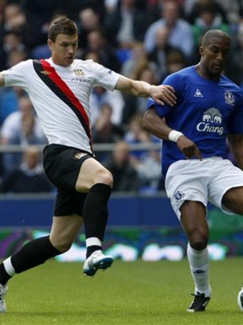 Manchester City's Edin Dzeko, left, vies for the ball with Everton's Sylvain Distin during their...