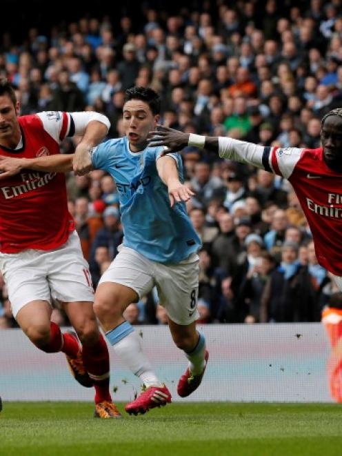 Manchester City's Samir Nasri (C) is challenged by Arsenal's Olivier Giroud (L) and Bacary Sagna....