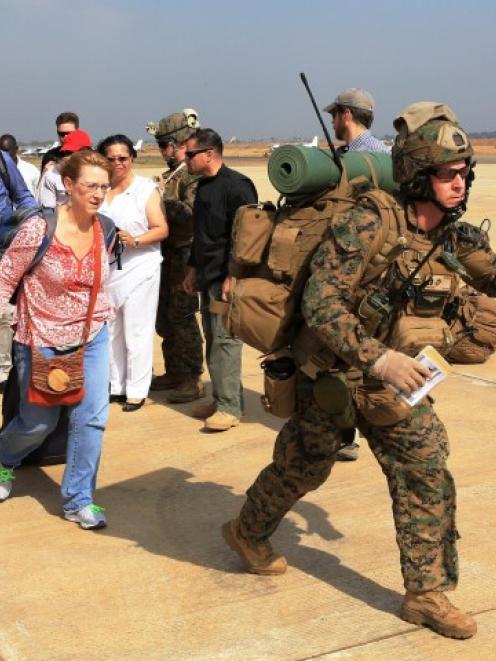 Marines guide US citizens down the flight line during a recent evacuation of personnel from the...