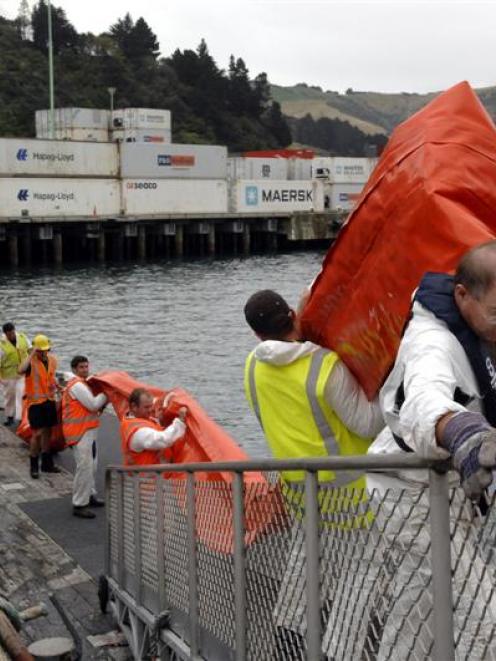 Mark Tully, of the Otago Regional Council, leads a team of people carrying a land sea boom used...
