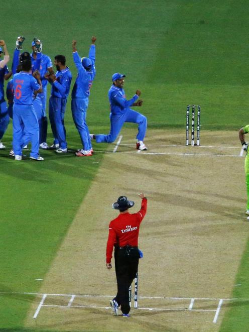 Members of India's cricket team celebrate after an electronic review confirmed the dismissal of...