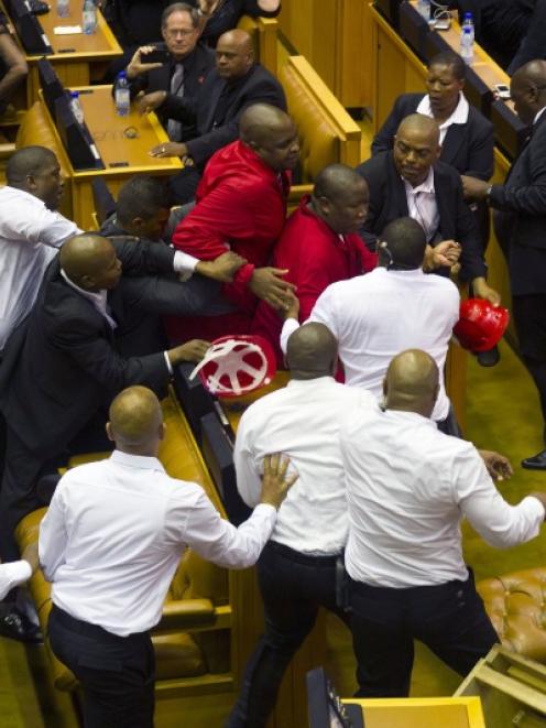Members of Julius Malema's Economic Freedom Fighters (EFF) (in red) clash with security officials...