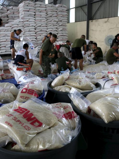 Members of the Armed Forces help pack food rations for typhoon victims.