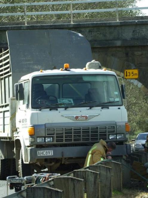 Members of the Balclutha Volunteer Fire Brigade work to untangle a truck from a roadside barrier...