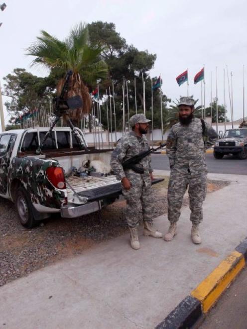 Members of the Libyan security forces stand guard close to the headquarters of the General...