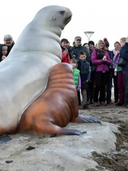 Members of the public gather in front of a remembrance statue of New Zealand sea lion ''Mum'', ...