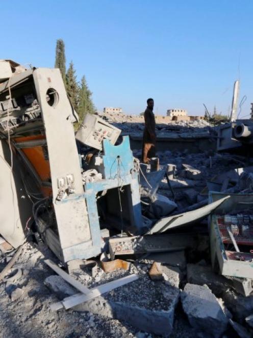 Men inspect a plastics factory damaged in what activists said were US-led air strikes in the...