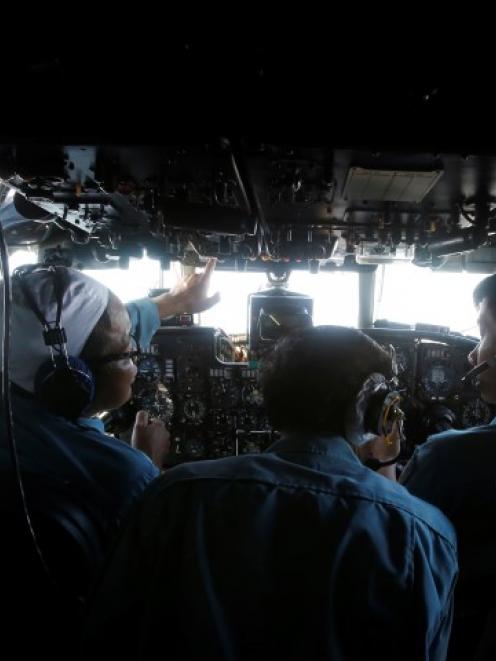 Military officers work in the cockpit of a Vietnam Air Force aircraft during the search for the...