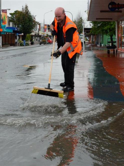 Mitre 10 assistant manager Ricky Bray, of Mosgiel, works to clear floodwater threatening Gordon...