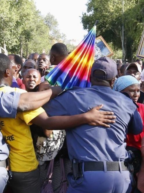 Mourners try to break through a police barrier attempt to view the body of former South African...