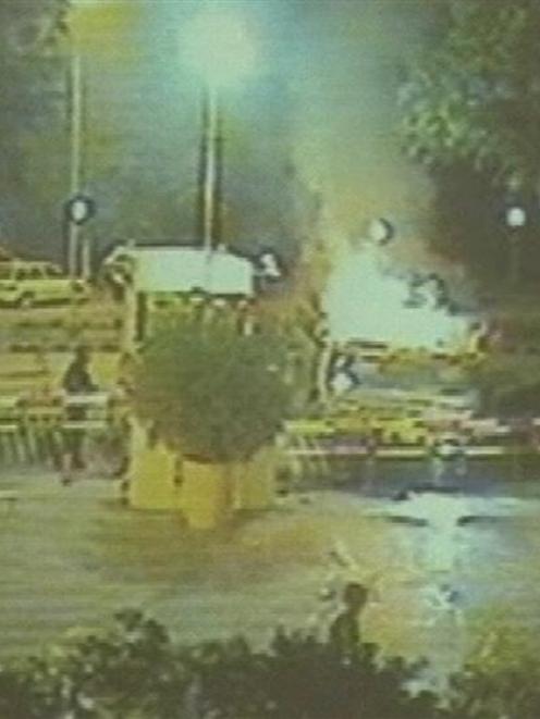 n this image taken by closed circuit TV footage guards look at a burning large dump truck, right,...