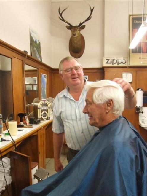 Neil McKenzie cuts Tony Selfe's hair yesterday in his Thames St hairdressing saloon. Photo by...