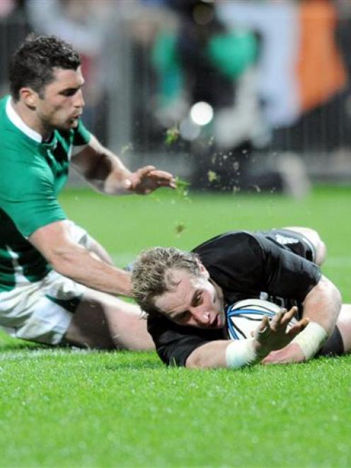 New Zealand halfback Jimmy Cowan scores the first of his two tries in the tackle of Ireland...
