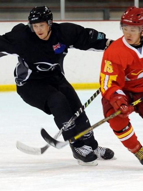 New Zealand's Andrew Cox (left) and China's Tianyu Hu compete for the ball during their ice...