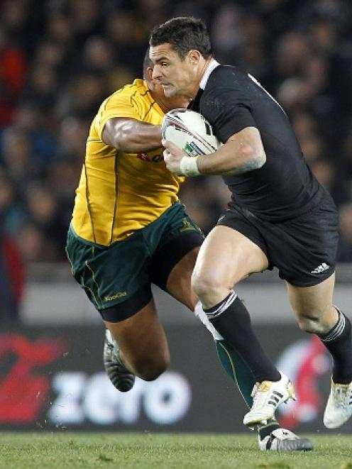 New Zealand's Dan Carter looks to fend off the tackle of Australia's Sekope Kepu during the Tri...