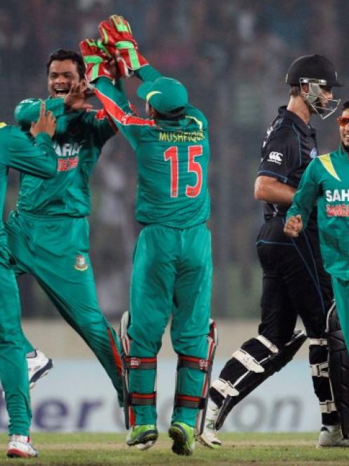 New Zealand's Grant Elliott (2nd R) leaves the field as Bangladesh players celebrate his...