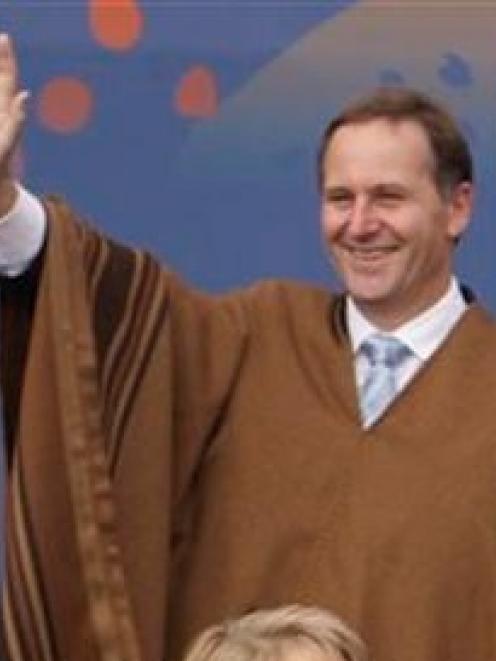 New Zealand's Prime Minister John Key wears a traditional Peruvian poncho as he waves during the...