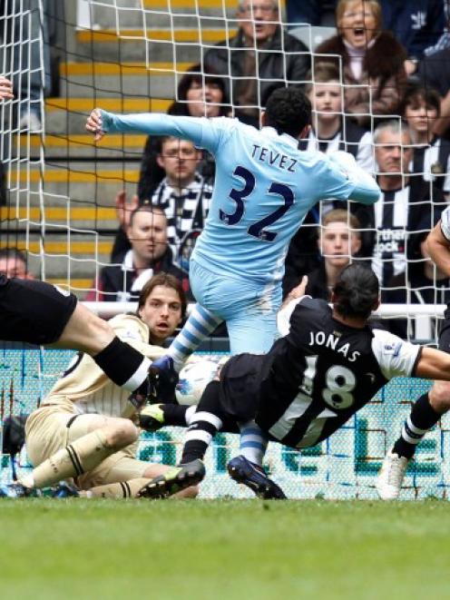 Newcastle United players tackle Manchester City's Carlos Tevez (C) as he tries to score during...