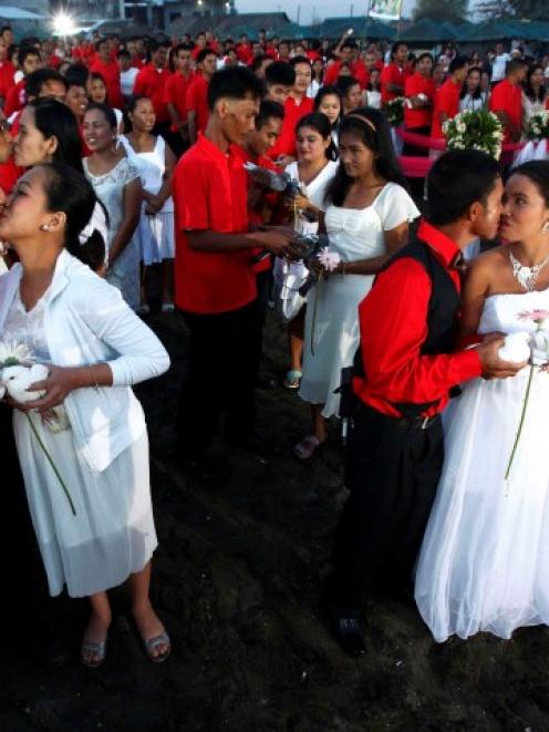 Newlywed couples kiss during a mass wedding ceremony at Rosario town, Cavite city, south of...